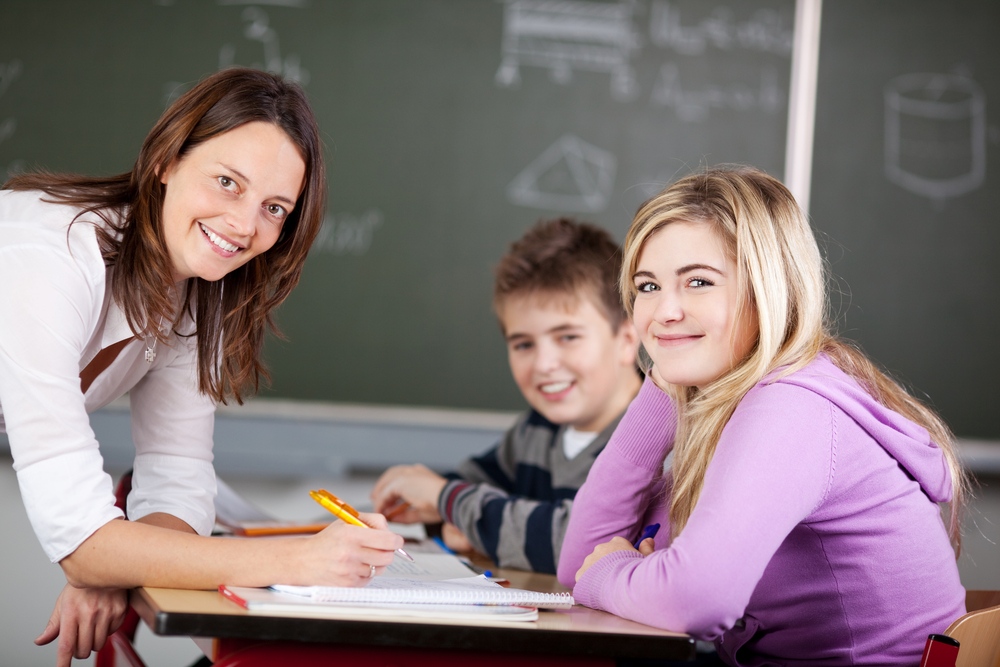 Portrait of female teacher and students smiling together in classroom